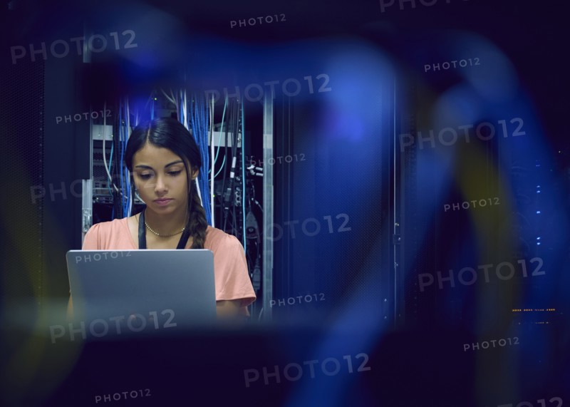 Female technician using laptop in server room
