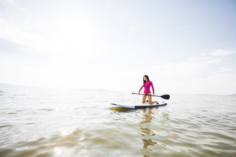 Woman kneeling on paddleboar in lake