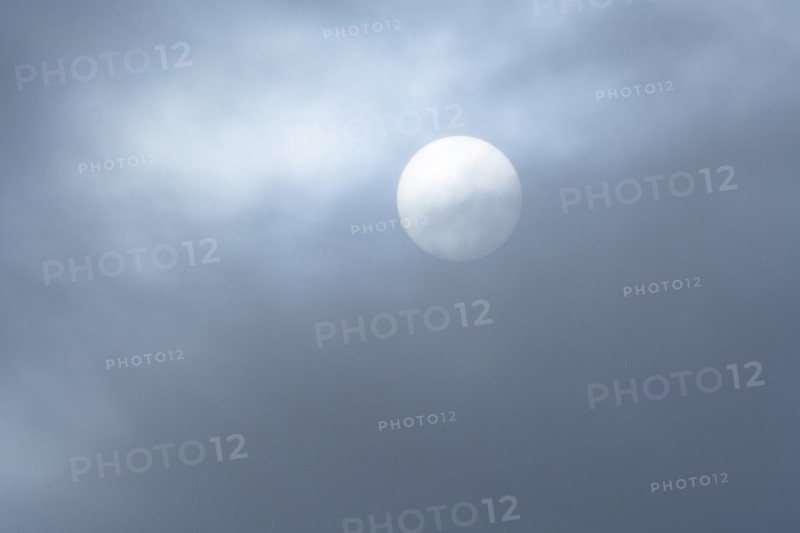 Hazy sun behind wispy clouds
