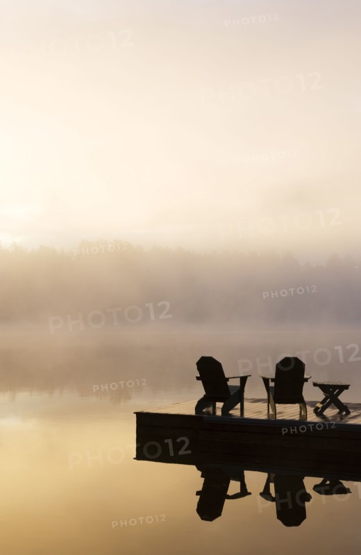 Silhouettes of adirondack chairs on pier