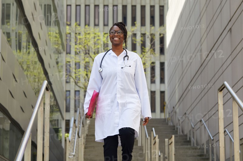 Portrait of smiling female doctor on steps in city