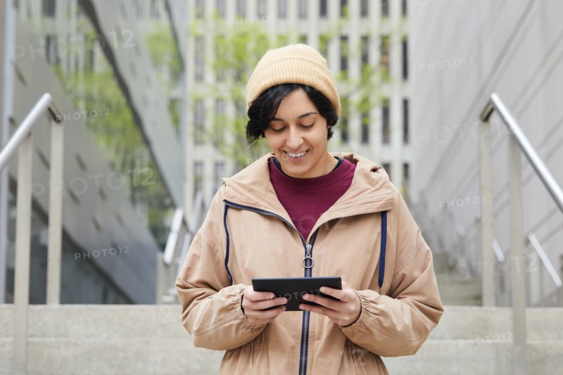 Smiling woman holding digital tablet on steps in city