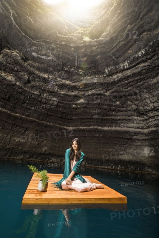 Portrait of woman sitting on floating dock near rocky coast