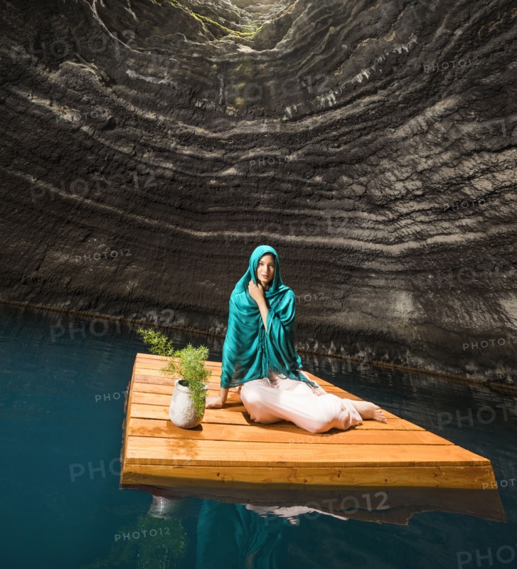 Portrait of woman sitting on floating dock near rocky coast
