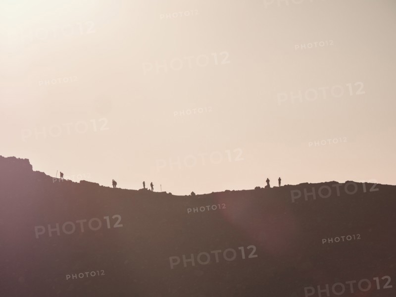 Silhouettes of hikers on mountain ridge at sunset