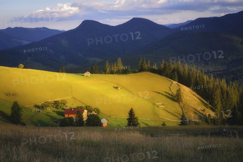 Houses in rural landscape in Carpathian Mountains at sunset