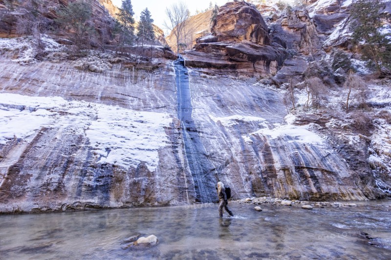 Senior woman crossing river while hiking in mountains