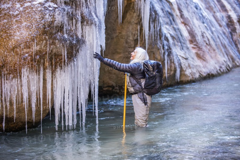 Senior woman exploring icicles while hiking in mountains