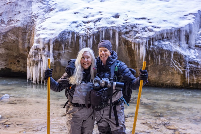 Senior couple crossing river while hiking in mountains