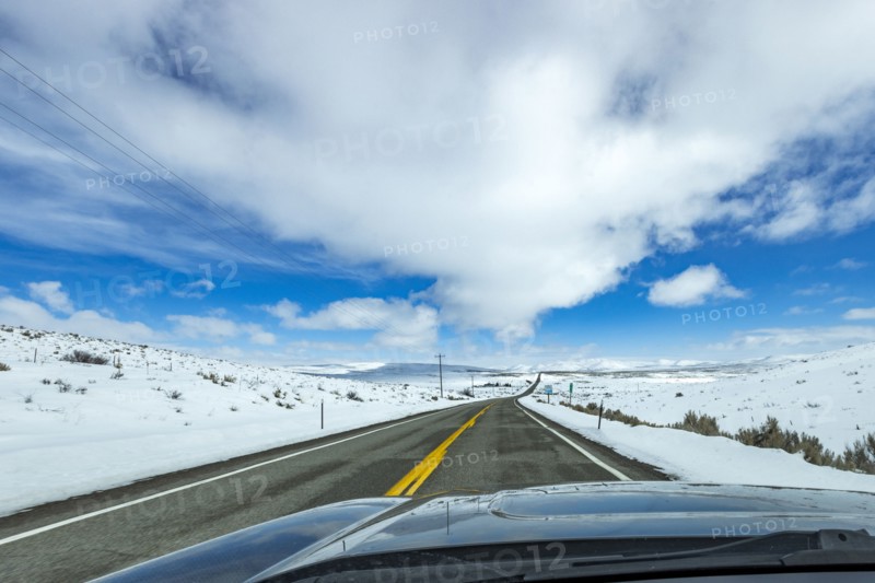 Highway through snow-covered landscape as seen from car