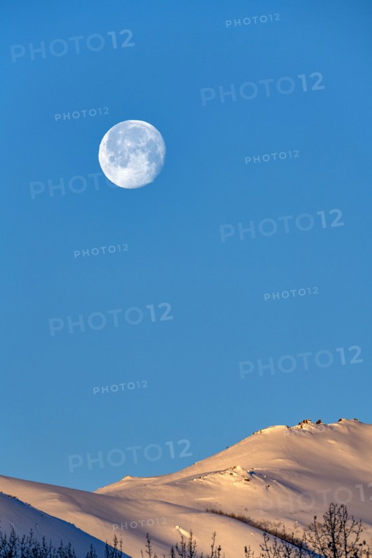 Full moon over snow-covered hills