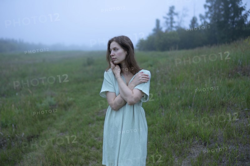 Woman standing in meadow on foggy day