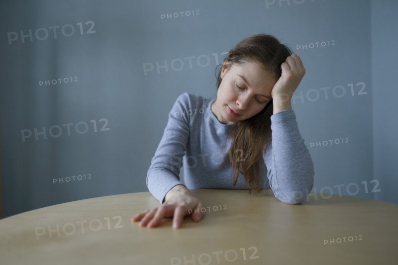 Portrait of tired woman sitting at round table at home