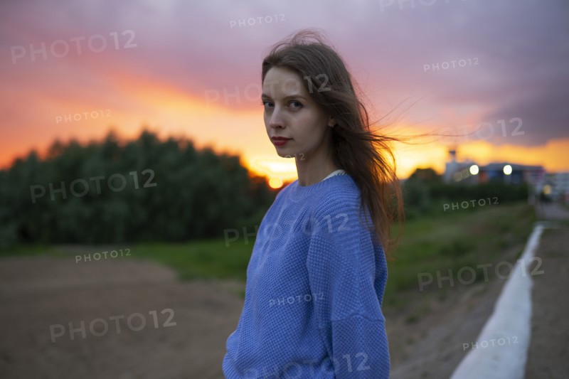 Portrait of beautiful woman standing in field at sunset