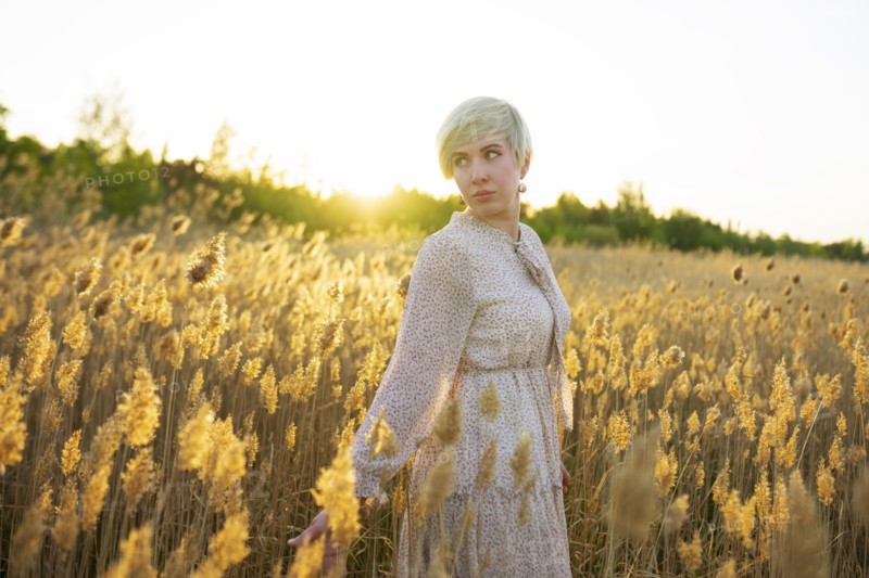 Portrait of woman standing in field at sunset