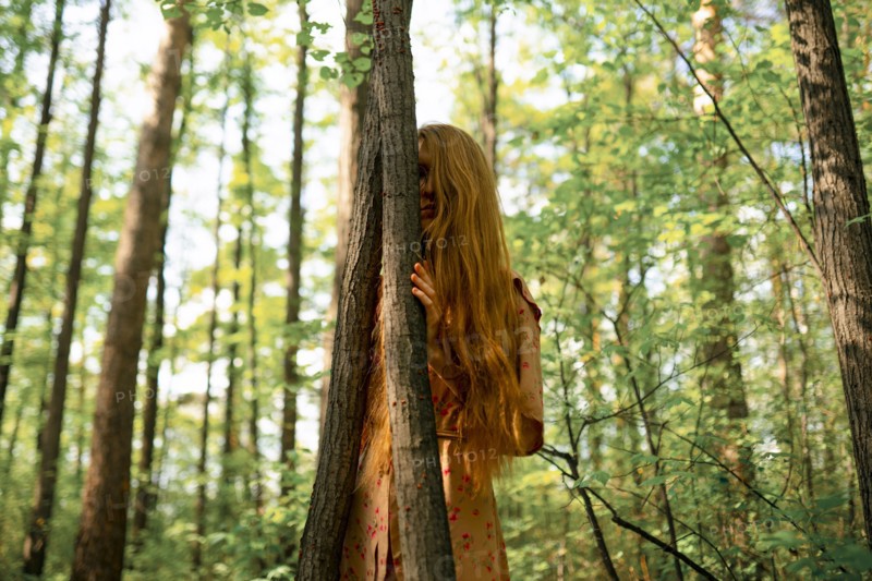 Young woman touching tree in forest