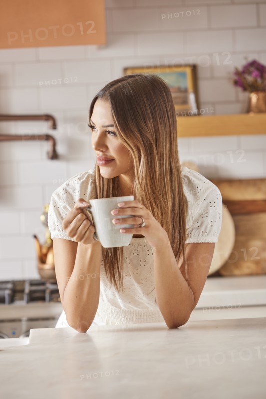 Smiling woman holding mug in kitchen