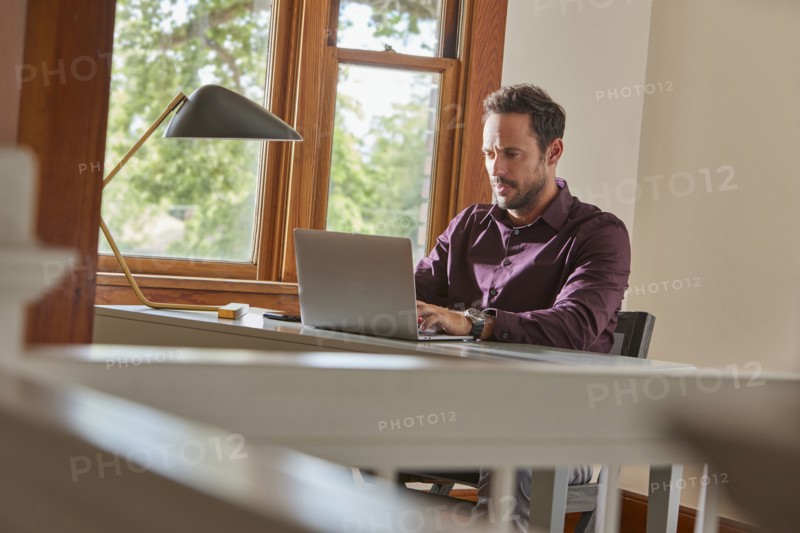 Man using laptop at table at home
