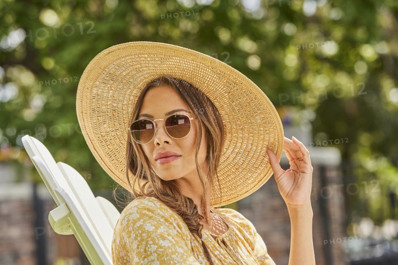 Woman in straw hat and sunglasses relaxing in park