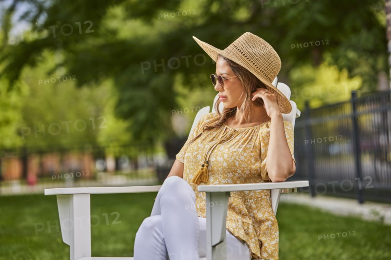 Woman in straw hat and sunglasses relaxing in park