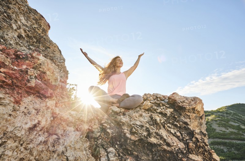 Mid adult woman meditating in mountains