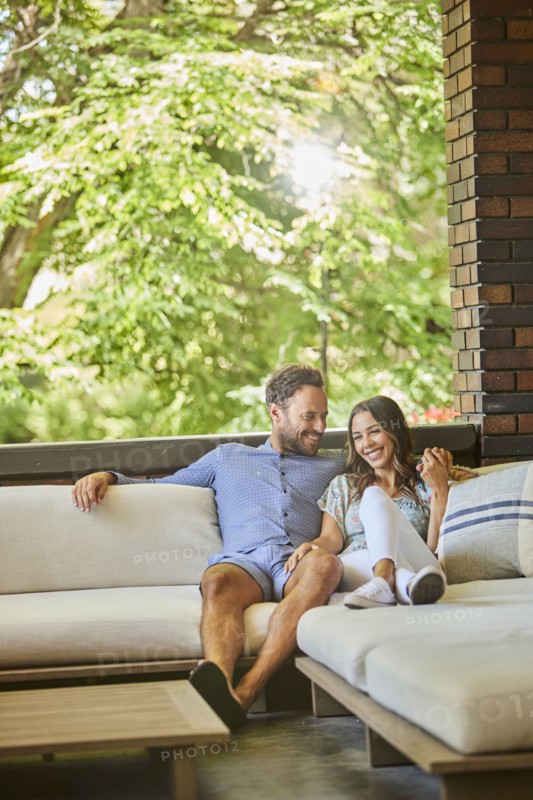 Mid adult couple relaxing on sofa on patio