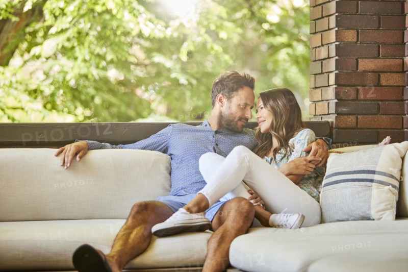 Mid adult couple relaxing on sofa on patio