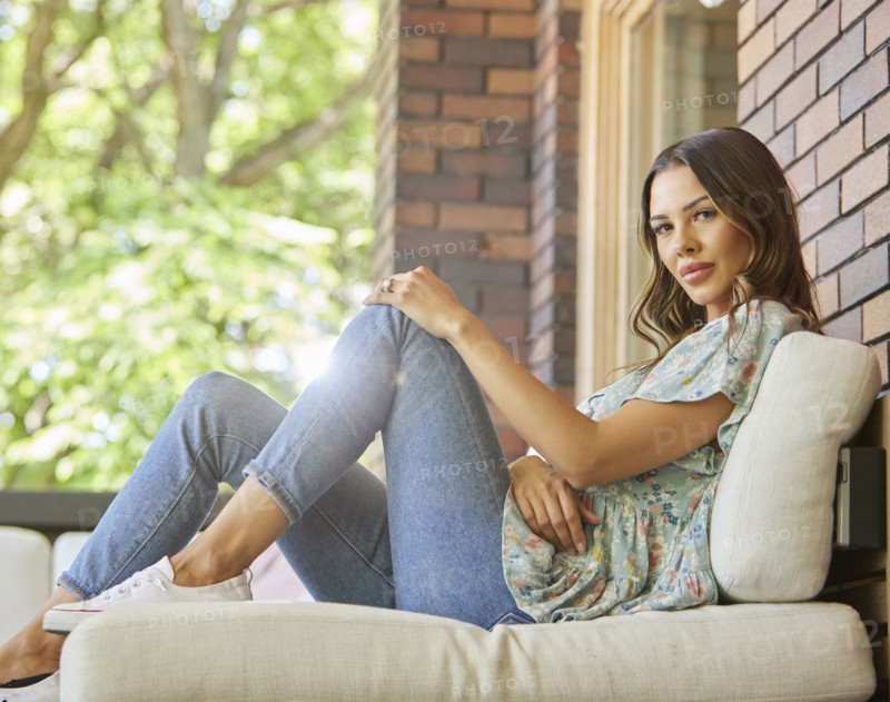 Portrait of mid adult woman relaxing on sofa on patio