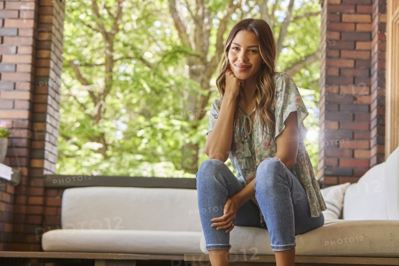 Portrait of mid adult woman relaxing on sofa on patio