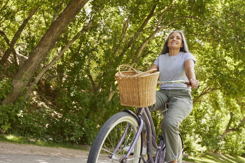 Smiling mature woman riding bicycle in park