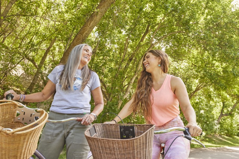 Mother and adult daughter riding bicycles in park