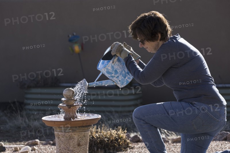 Woman filling bird bath with watering can