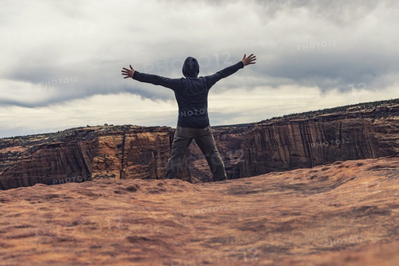 Man spreading arms in canyon