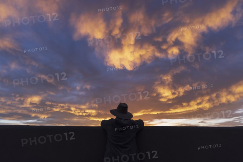 Silhouette of man in hat looking at sunset