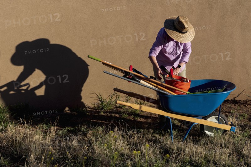 Senior woman with gardening equipment in desert garden