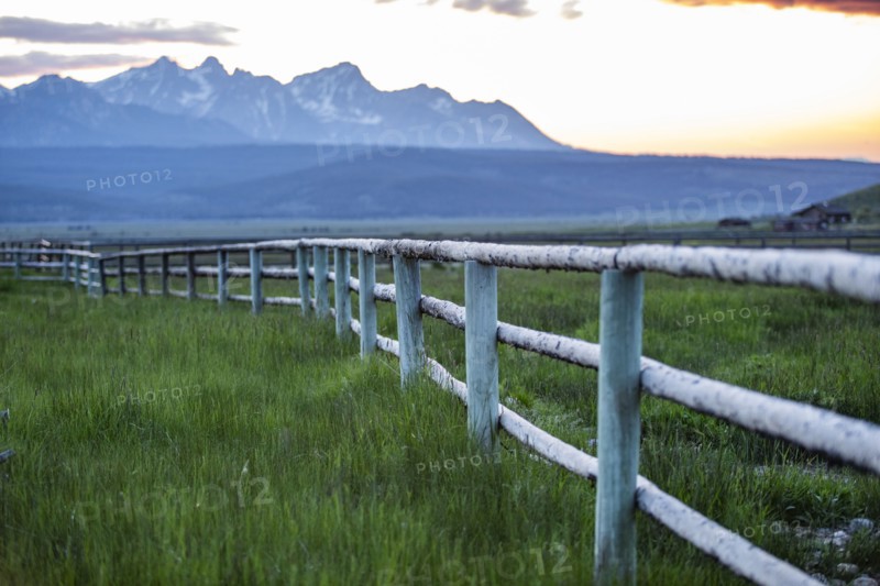 Scenic view of Sawtooth Mountains and meadow with rail fence at sunset