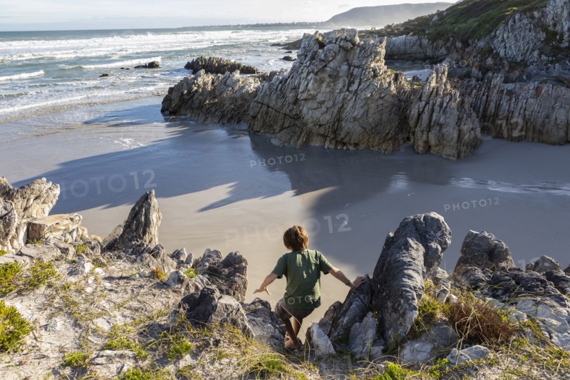 Boy exploring rocky coastline in Voelklip Beach