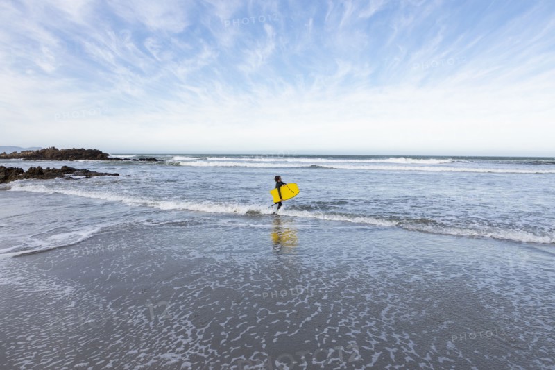 Boy entering Atlantic Ocean with body board