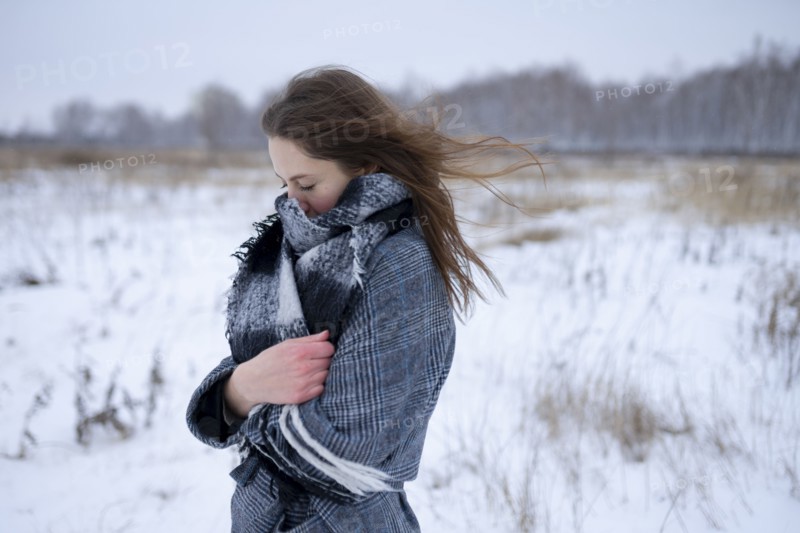 Portrait of freezing woman standing in snowy meadow