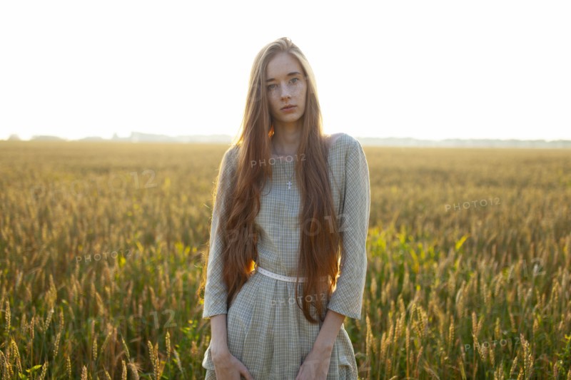 Portrait of young woman looking at camera while standing in field