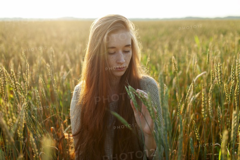 Portrait of young woman looking at cereal plants in field