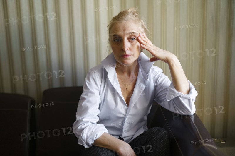 Serious blonde woman sitting on sofa in living room