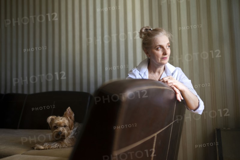 Woman sitting on sofa with Yorkshire terrier at home