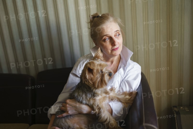 Woman sitting on sofa and holding Yorkshire terrier