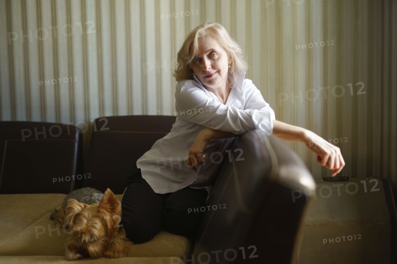 Woman leaning on sofa next to Yorkshire terrier in living room