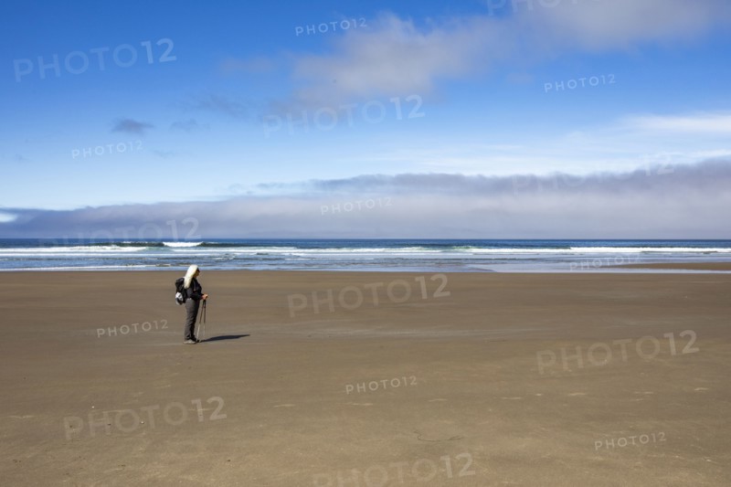 Woman standing on sandy beach and looking at view