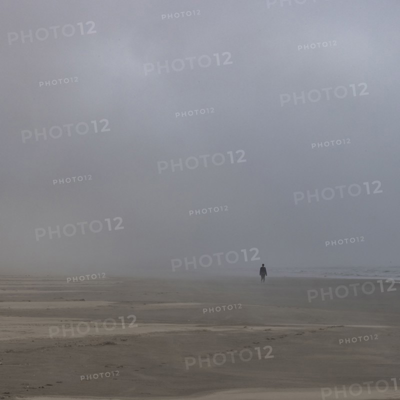 Misty figure walks along beach