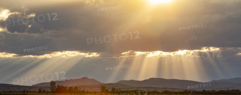 Rays from setting sun shining on fields and hills