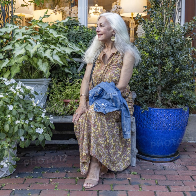 Senior blonde woman sitting on bench in shopping district