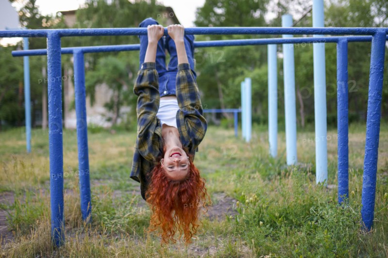 Redhaired woman hanging on bars at playground